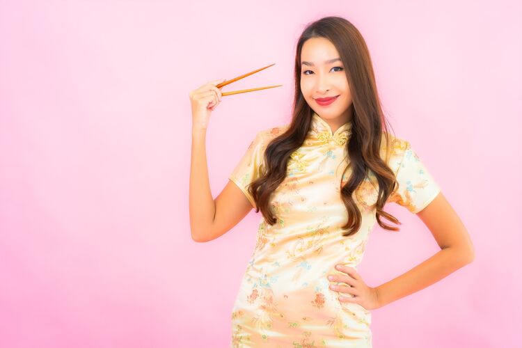 饥饿在粉红色的墙上画一幅美丽的亚洲年轻女子拿着筷子服装举行年轻人