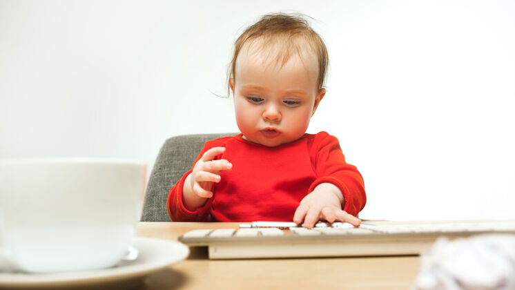 桌子辛苦的一天孩子女婴坐在键盘的现代电脑或笔记本电脑在白色工作室笔记本电脑教育可爱