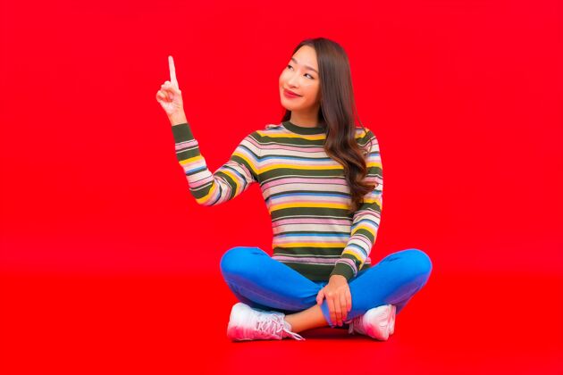 时尚美丽的亚洲年轻女子在红色隔离墙上微笑中国人健康微笑