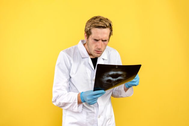 笔记本电脑前视图男性医生正在检查黄色桌子上的头骨x光医疗外科covid-男性医疗帅哥