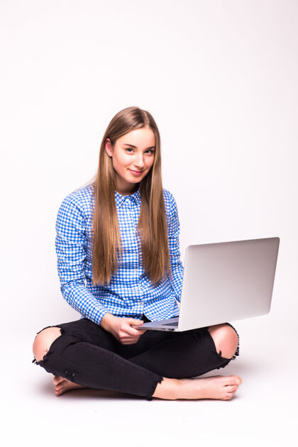 互联网年轻随意的女人坐下来微笑着拿着笔记本电脑隔离在白墙上电脑休闲无线