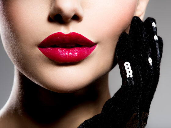 时尚用红色口红和黑手套在脸颊上失去女人的嘴唇吸引力高加索手套