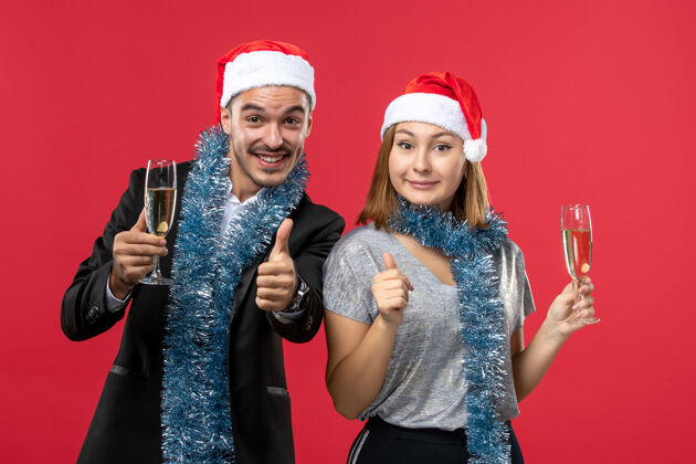 快乐正面图年轻夫妇在红地板上庆祝新年爱圣诞派对饮料风景肖像微笑