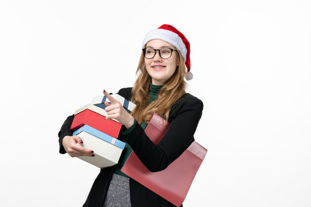 商务女性正面图年轻女性手持节日礼物在白墙上礼品书新年观点笔记本电脑年轻女性