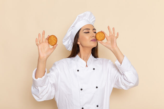 工作身穿白色厨师服的年轻女厨师正拿着饼干站在白墙上套装微笑工人