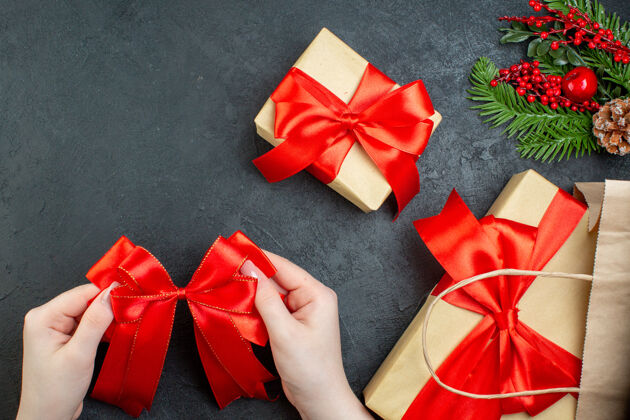 鞠躬上图是圣诞节的气氛与美丽的礼物和黑色背景上的红丝带圣诞节风景车轮