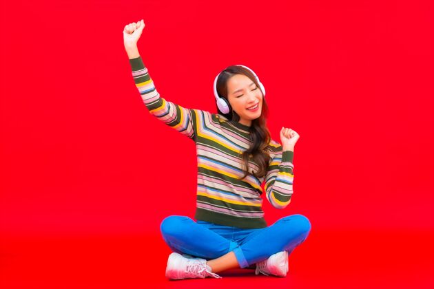 手机肖像美丽的亚洲年轻女子使用智能手机和耳机听音乐享受成人耳机