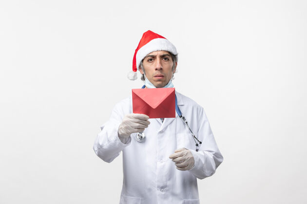 圣诞节正面图男医生拿着白墙上的信封病毒情感共价-健康制服医学病毒