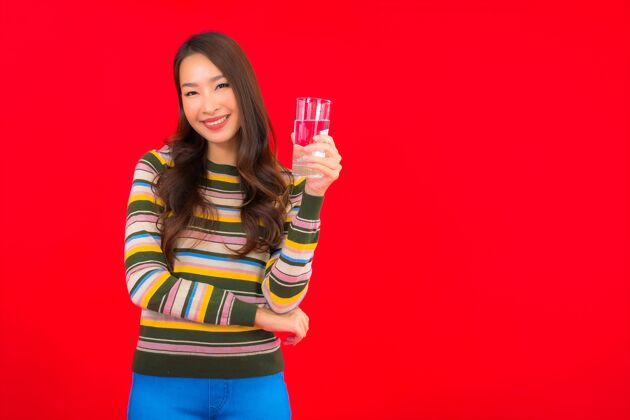 生活在红墙上画一幅美丽的亚洲年轻女子的画像 戴着饮水杯矿物杯子健康
