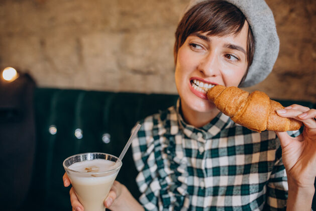 法国在咖啡馆喝拿铁吃羊角面包的法国女人年轻美丽温暖