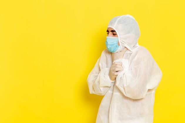 正面身穿白色特殊防护服 戴着黄色面罩 喉咙有问题的男性科学工作者的正面图面具人科学