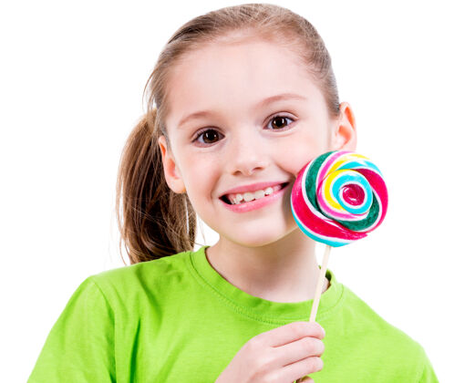 人身着绿色t恤和彩色糖果的微笑小女孩的肖像-白色隔离快乐糖果甜食