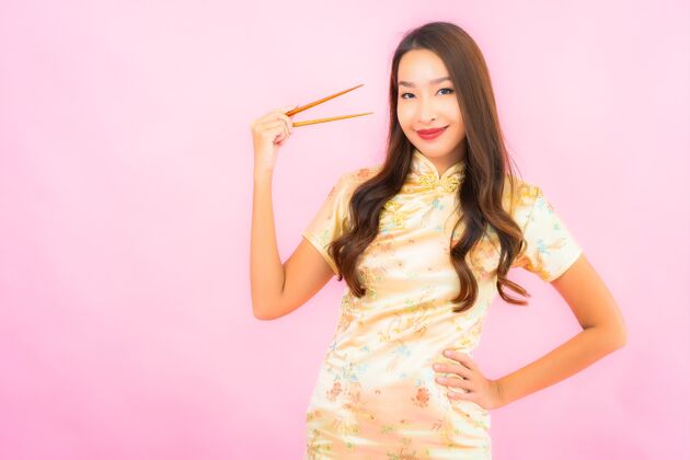 饥饿在粉红色的墙上画一幅美丽的亚洲年轻女子拿着筷子服装举行年轻人