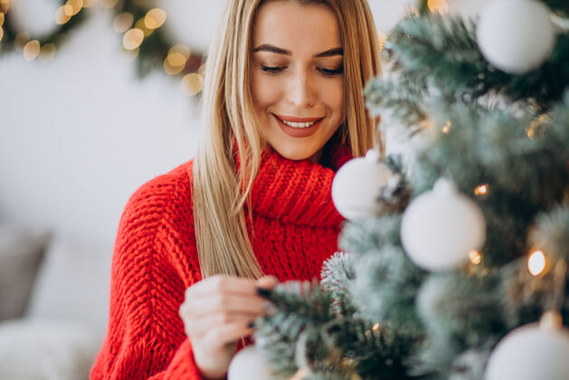 积极装饰圣诞树的年轻女人装饰圣诞树盒子毛衣