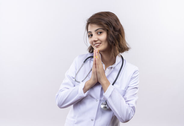 抱着身穿白大褂 手持听诊器的年轻女医生手牵手祈祷 感慨感恩和幸福谢谢祈祷外套
