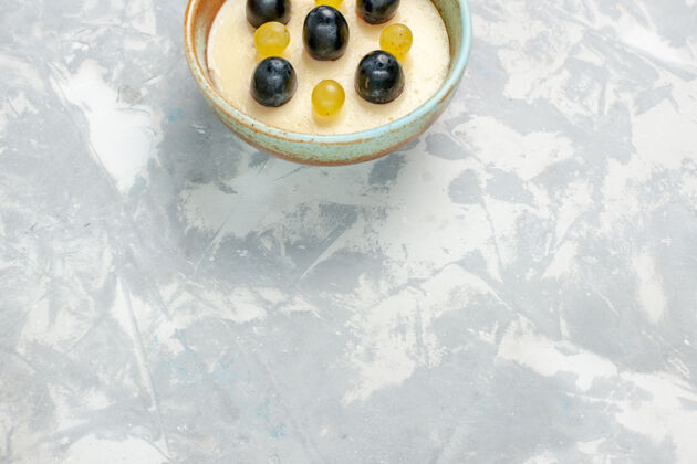顶部半顶视图美味的奶油甜点 顶部有水果 在白色表面的小锅里酸奶奶油甜点