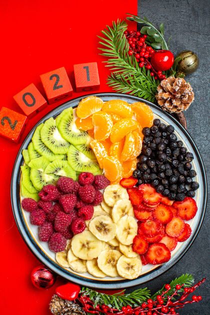 水果上图为收集新鲜水果的餐盘装饰配件杉木树枝和数字圣诞袜在黑色背景上的红色餐巾上数字冷杉餐盘