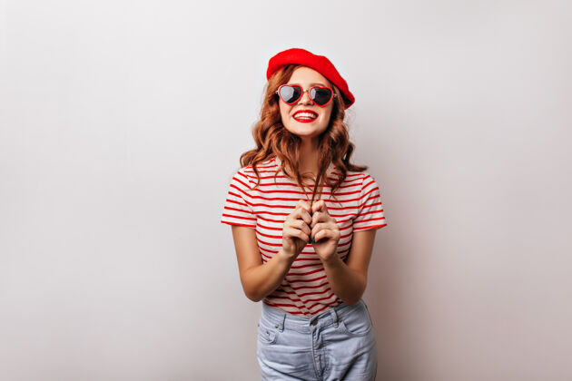 红发快乐的高加索女孩戴着贝雷帽优雅的法国女人戴着墨镜微笑着摆姿势表情室内贝雷帽