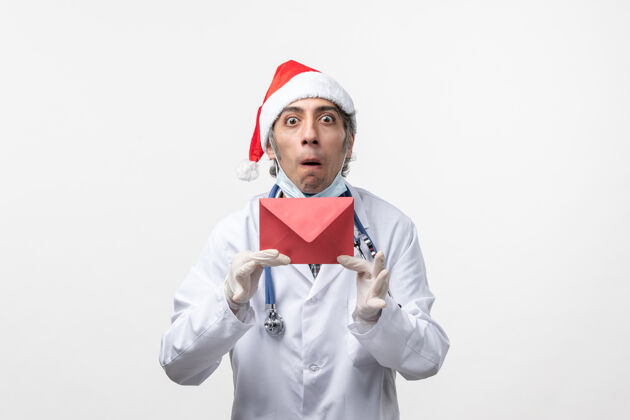 圣诞节正面图男医生手持红包白墙健康冠状病毒成人工人工作