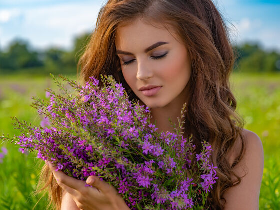 长发一位白人妇女在大自然中放松的特写照片一位年轻女子在户外拿着一束花一位女孩在田野里 手里拿着薰衣草花女人夏天阳光