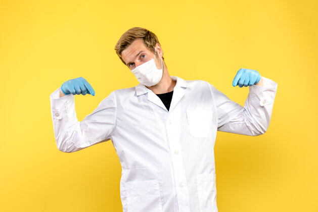 外套正面图黄色背景上的男医生指的是大流行的科维德健康医生冠状病毒医生人