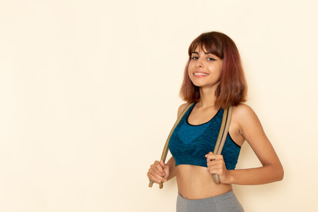 运动身穿蓝色衬衫的年轻女性在浅白的墙壁上微笑 身体健康私人教练女孩模特