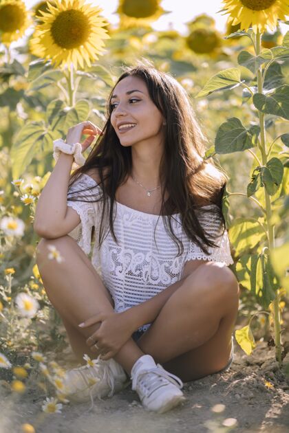 明亮一位年轻漂亮的白人女性在向日葵地里摆姿势的垂直镜头开花活力风景