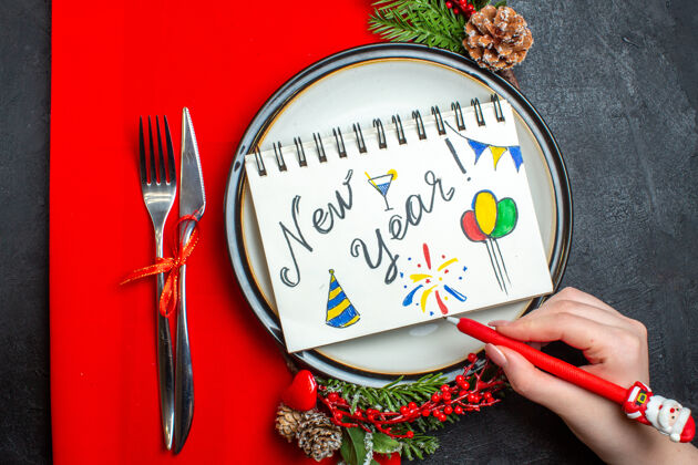 地图上图为笔记本 餐盘上有新年文字和图画 装饰配件杉木树枝和餐具放在红色餐巾上餐具笔记本视图