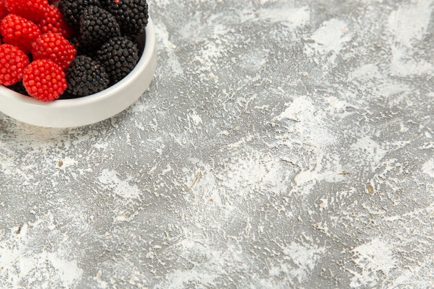糖顶部近距离观察新鲜浆果 白色表面上有甜甜的糖果糖果甜点黑莓