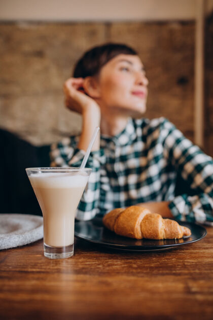 美丽在咖啡馆喝拿铁吃羊角面包的法国女人肖像快乐女人
