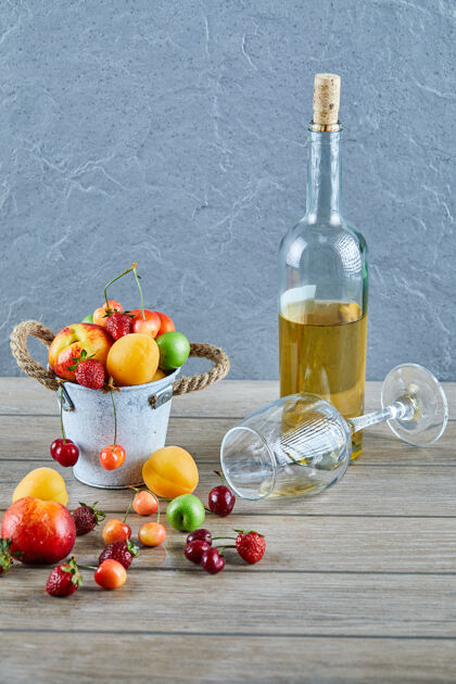 草莓木桌上有一桶夏天的新鲜水果 一瓶白葡萄酒和空杯子酸浆果桌子