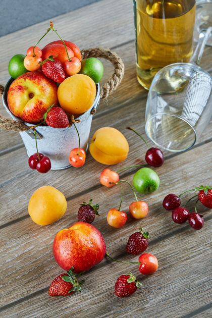 浆果木桌上有一桶夏天的新鲜水果 一瓶白葡萄酒和空杯子多汁饮料酒精