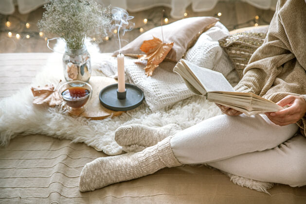 舒适惬意的秋天在家 一个女人拿着一本书在休息一种惬意的生活方式身体部位在作曲茶放松袜子