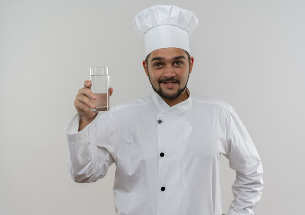 微笑面带微笑的年轻男厨师身着厨师制服 手里拿着一杯隔离在白色空间里的水男性厨师年轻