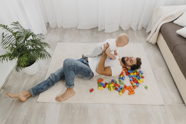 男人高角度的爸爸在家和宝宝在地板上玩养育小男性