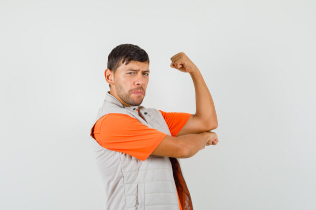 严肃年轻男性穿着t恤衫 夹克衫展示手臂肌肉 看上去很有力量前视图手臂办公室男性