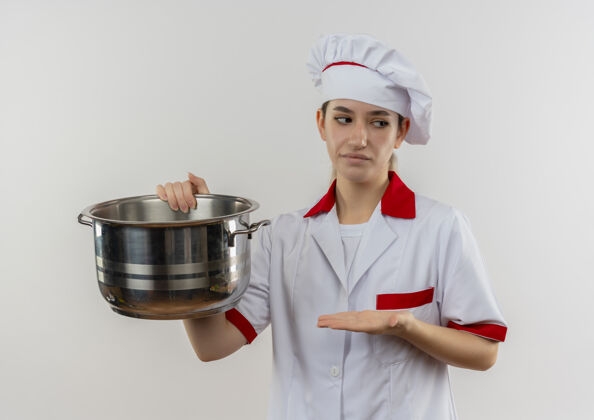 年轻年轻漂亮的厨师穿着厨师制服 拿着锅 用手指着它 看着旁边的空白处厨师厨师手