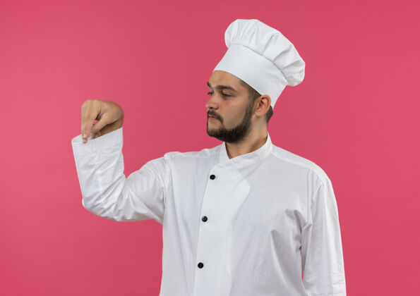 添加年轻的男厨师身着厨师制服 一边加盐 一边看着粉红色的空间隔离盐制服外观