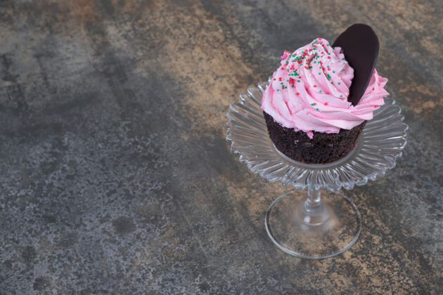 美味粉红色奶油蛋糕放在大理石的玻璃盘上曲奇糖果巧克力