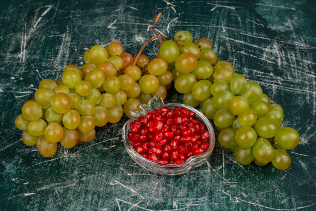 美味绿色的葡萄和石榴籽在大理石表面成熟种子红色
