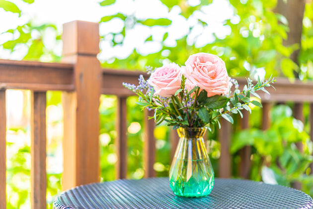 玫瑰桌上花瓶里的美丽花朵装饰着花园的景色花朵花园绿色