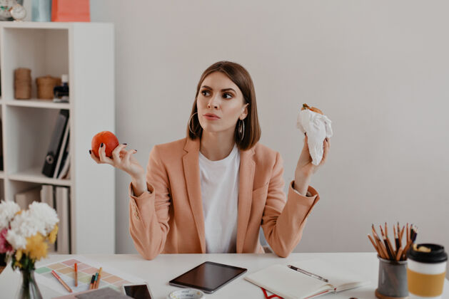 成年人办公室里留着短发的女士的画像有思想的女商人选择吃汉堡包或健康的苹果企业家女性欢呼