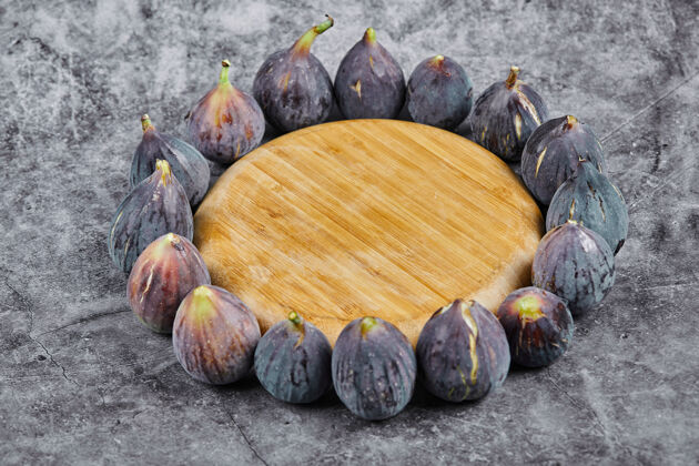 有机紫色无花果围绕在大理石的木板上新鲜热带盘子