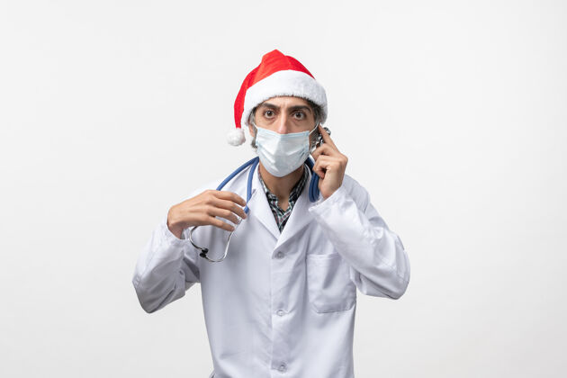 制服正面图：戴着口罩的男医生在白墙上假日柯维德大流行病毒圣诞节视图男人