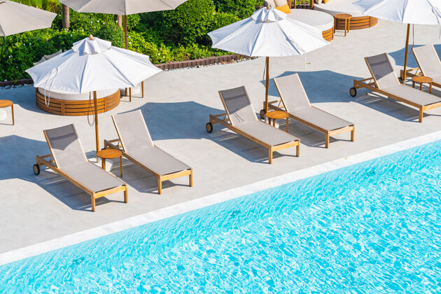 酒店雨伞和躺椅环绕着酒店度假村的室外游泳池 靠近海边的海洋游泳池海滩海洋