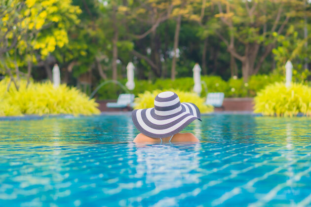 度假村肖像美丽的亚洲年轻女子放松微笑休闲围绕室外游泳池近海人酒店放松