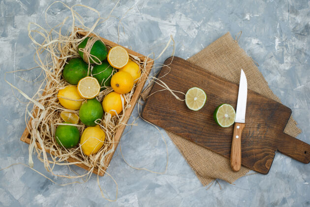 果壳一些酸橙和柠檬 用餐巾和刀放在砧板上叶子成熟果汁