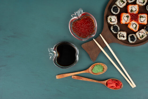 腌制生姜把寿司盘 酱油和红鱼子酱放在蓝色的表面上寿司食物腌制