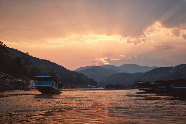 日落美丽的拍摄湄公河与船在夕阳的前景在白奔 老挝河流美丽亚洲