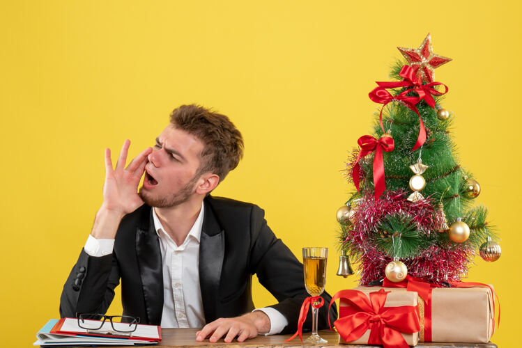 电话正面图男性工人坐在他工作的地方后面呼叫黄色圣诞节地点工作